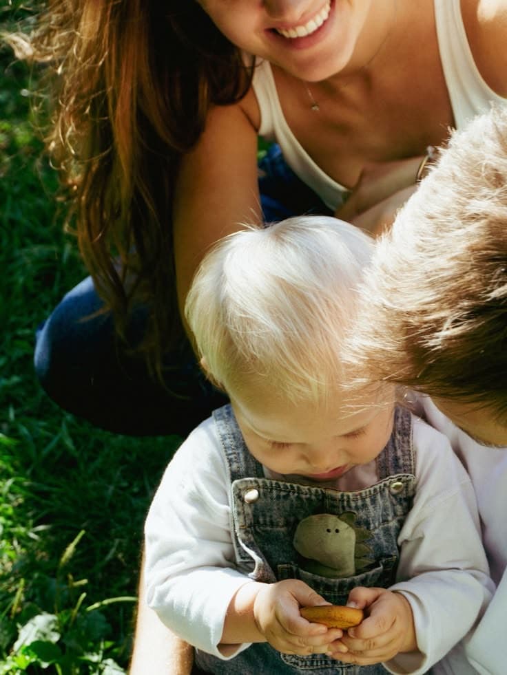 A smiling mum on the grass with two little children